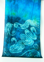 Load image into Gallery viewer, A_vertical_shawl_display_featuring_a batik_design_of_stylized_white_swans and_swirling_patterns_over_a_vibrant_blue_turquoise_and_teal_watercolor_background.