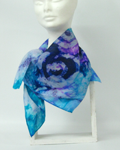 Load image into Gallery viewer, a_silk_scarf_hand_painted_with_celtic_design_at_frontign_blues_lilacs_violet_bright_aqua_scarf_tied_around_neck_showing_spiral_design
