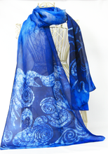 Load image into Gallery viewer, A_sheer_blue_shawl_with_swan_and_swirl_design_draped_over_a_mannequinn_in_front_of_a_white_background
