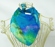 Load image into Gallery viewer, silk_scarf_in_shades_of_turquoise_worn_around_the_neck_of_the_mannequin_infront_of_a_white_background
