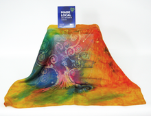Load image into Gallery viewer, A_vibrant_multicolored_scarf-draped_to_show_its_full_shape-against_a_white_background_featuring_a_central_tree_design_with_a_blue_card_reading_'MADE LOCAL'_is_propped_up_at_the_top.
