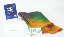 Load image into Gallery viewer, A_sillk_scarf_folded_and_draped_on_a_white_gift_box_with_Louise_Loughman_artist_card_and_the_madeLocal_sign_the_perfect_way_to_start_your_small_wearable_art_collection_a_one_off_scarf
